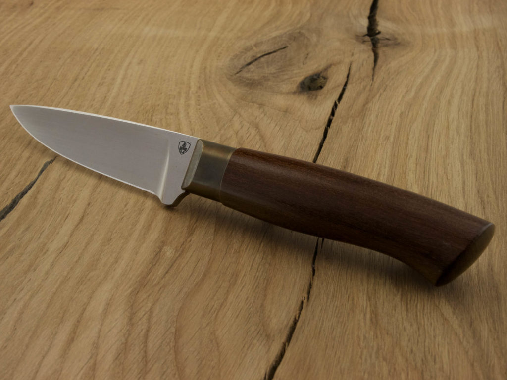 J052-3 A hand forged outdoor knife with an African Coral Wood handle and blade from D2 steel lays on a wooden board.