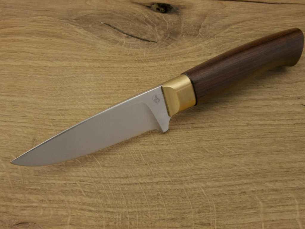J052-6 Ein handgeschmiedetes Outdoor-Messer mit einem Griff aus Padouk und einer Klinge aus D2-Stahl liegt auf einem Holzbrett.