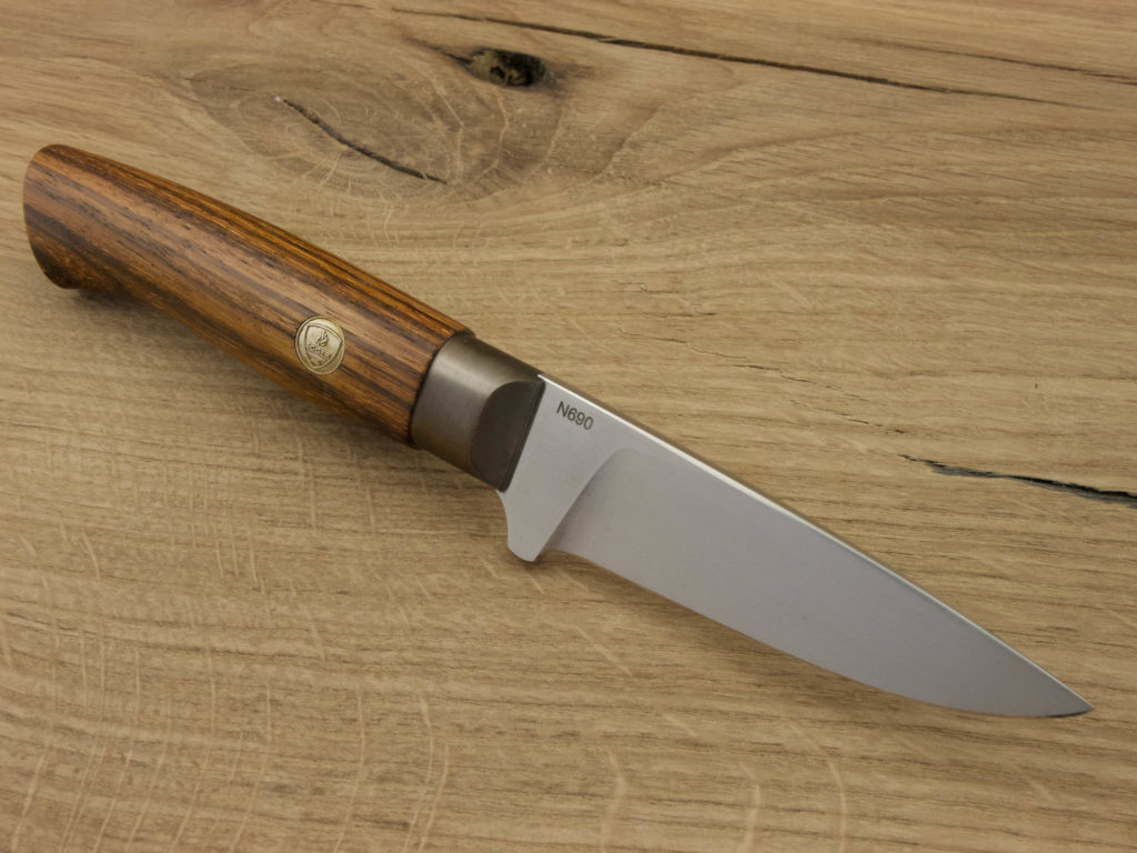 J053-3 Ein handgeschmiedetes Outdoor-Messer mit einem Griff aus Zebrano-Holz und einer Klinge aus N690-Stahl liegt auf einem Holzbrett.
