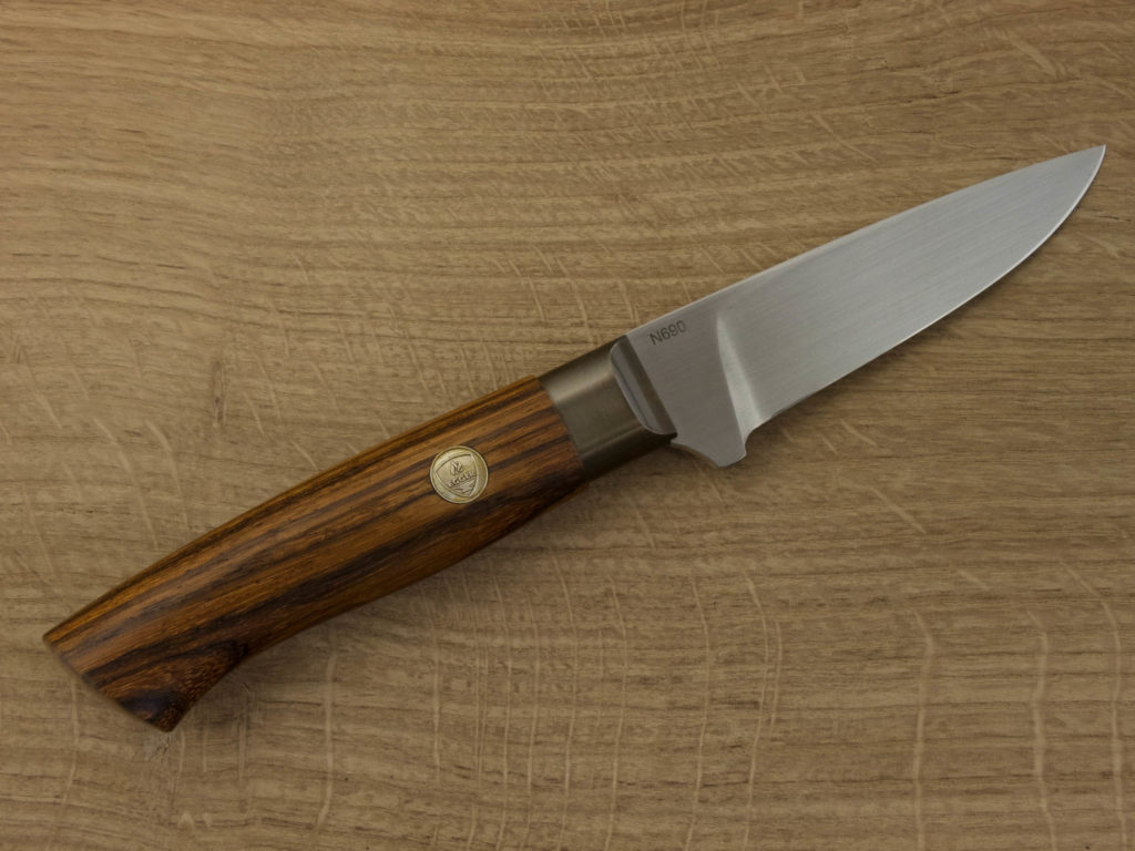 J053-4 A hand forged outdoor knife with a Zebra wood handle and blade from N690 steel lays on a wooden board.
