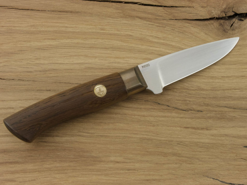 J054-1 A hand forged outdoor knife with a smoked oak handle and blade from N690 steel lays on a wooden board.
