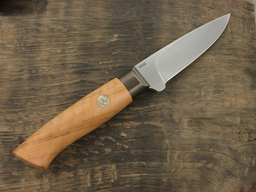 J055-1 Outdoormesser mit einem Griff aus Olivenholz und Klinge aus N690. Stahl liegt auf einen Eichenbrett